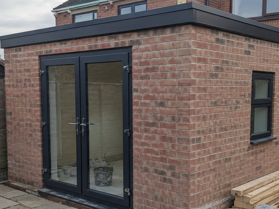 Brick garden room with a flat roof and anthracite french doors
